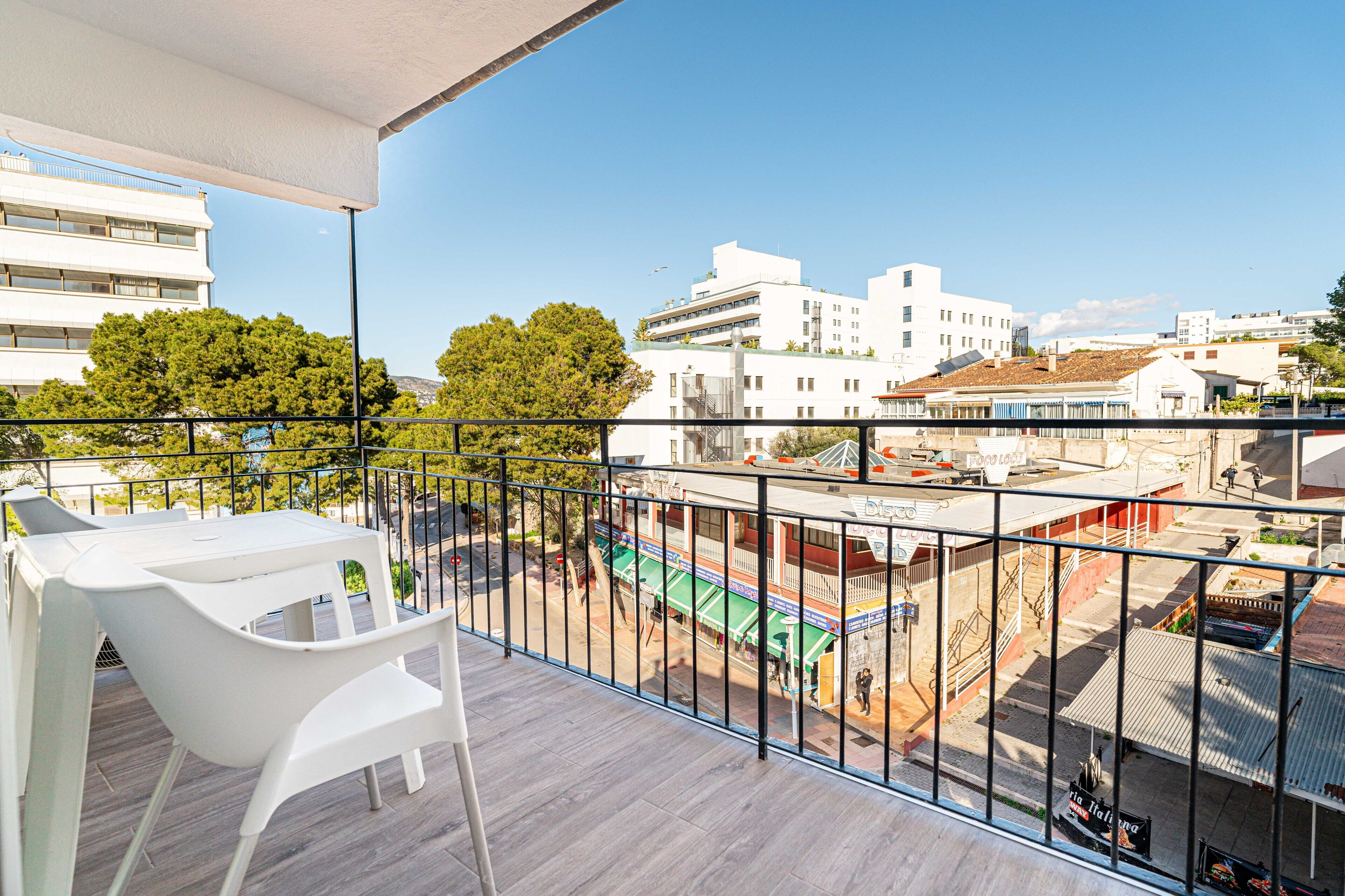 A balcony with a view of a cityscape, including buildings and trees.