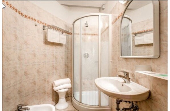 A bathroom with a glass-enclosed shower, a sink, and a mirror. - Hotel Arno Bellariva (Florence)
