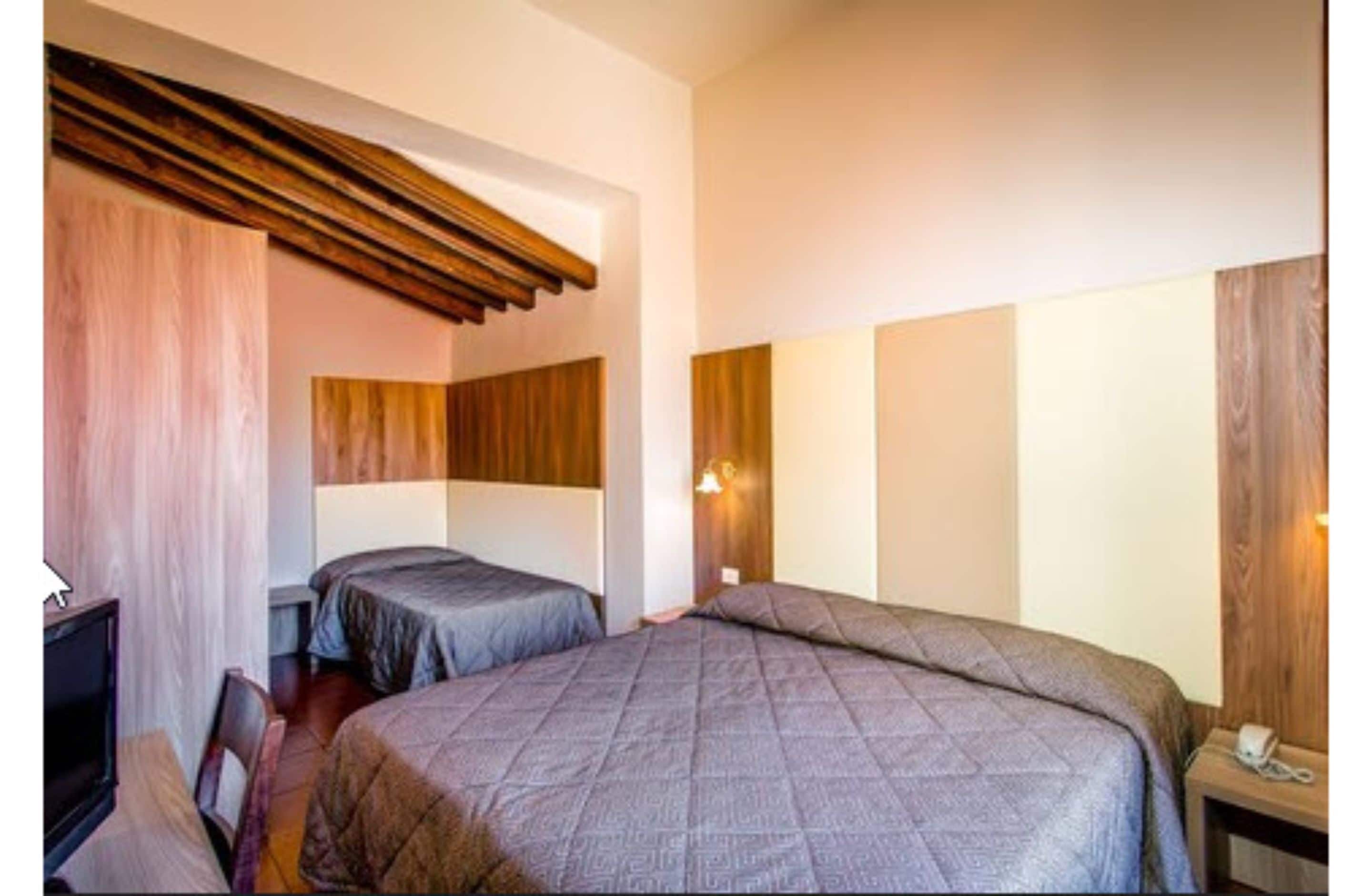 A hotel room with two beds, a desk, and a chair.