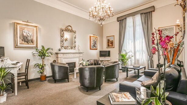 A spacious living room with a fireplace, comfortable seating, and decorative plants. - Hotel Arno Bellariva  (Florence)