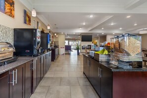 Un área de cocina moderna con una isla central, una cafetera y varios dispensadores de comida.
