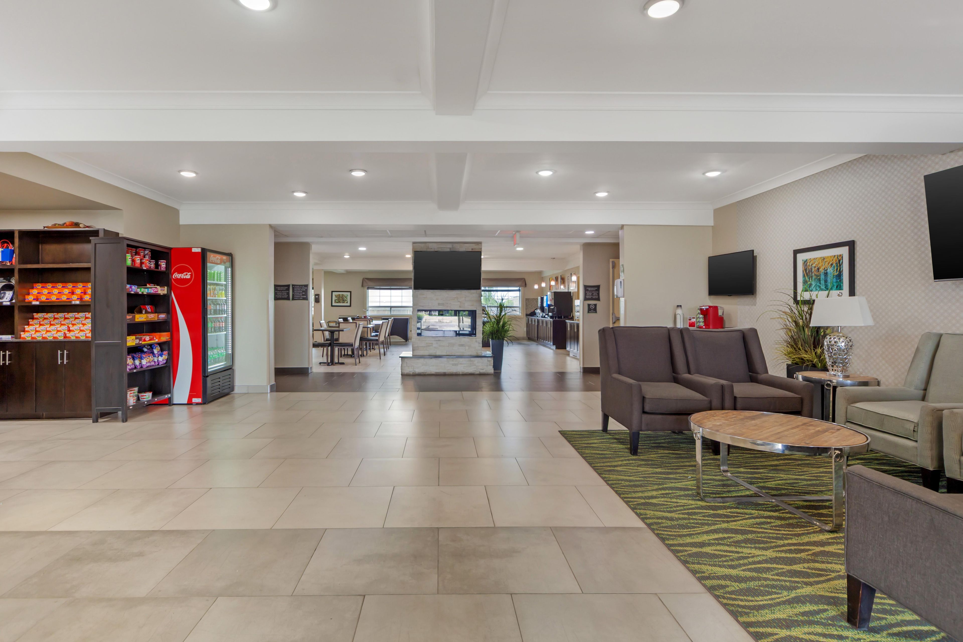 A hotel lobby with a seating area, a vending machine, and a television on the wall.