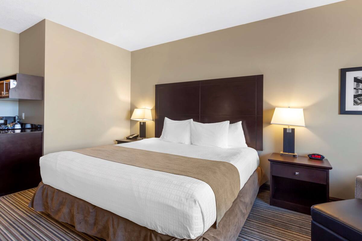 A hotel room with a large bed, two bedside tables with lamps, a small desk, and a chair.