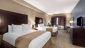 A hotel room with two beds, a desk, a TV, and a chair.