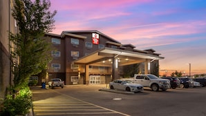 A hotel with a modern design, a covered entrance, and a parking lot with several cars.