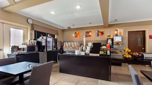 A modern cafe with a central counter, seating area, and kitchen equipment.