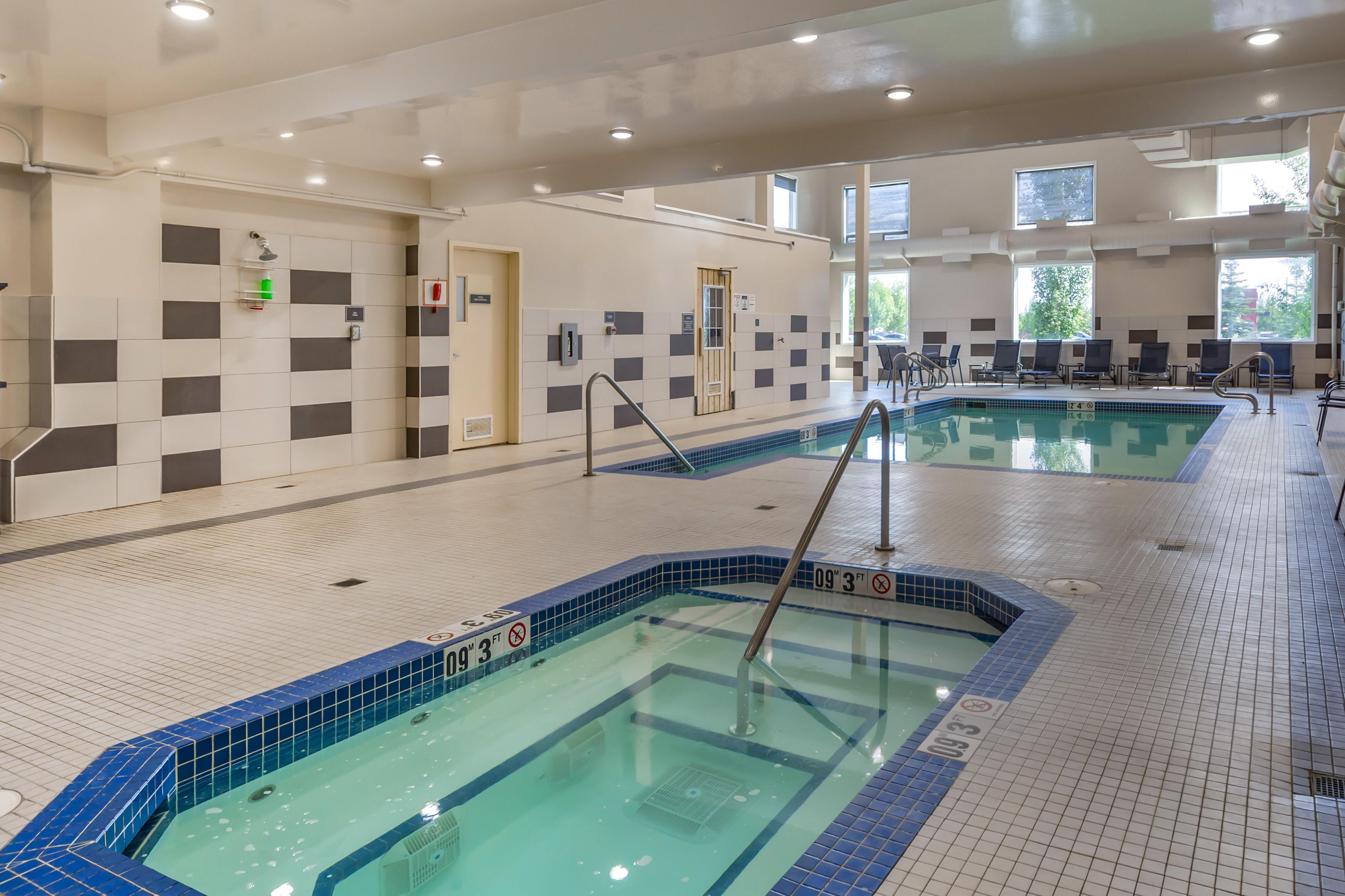 An indoor swimming pool with clear water, tiled walls, and a tiled floor.