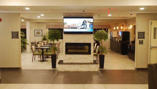 A lobby with a fireplace, seating area, and a television mounted above it.