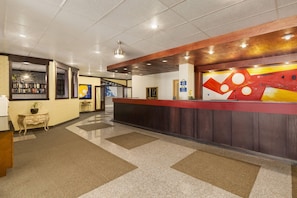 A hotel reception area with a check-in counter, a bookshelf, and a decorative wall. - Days Inn by Wyndham Vermilion (Vermilion)