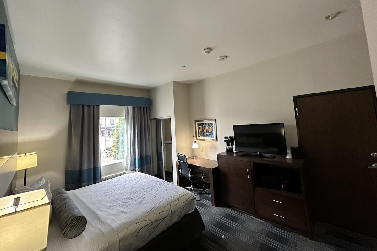 A hotel room with a bed, a desk, a television, and a wardrobe.