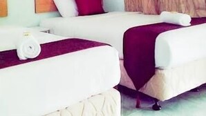 Quarto de hotel com duas camas, cabeceira de madeira, pintura de uma rosa e cortina.