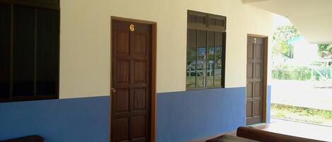 Un pasillo con tres puertas de madera, cada una con un ventanal encima. Hay bancos a lo largo del pasillo.