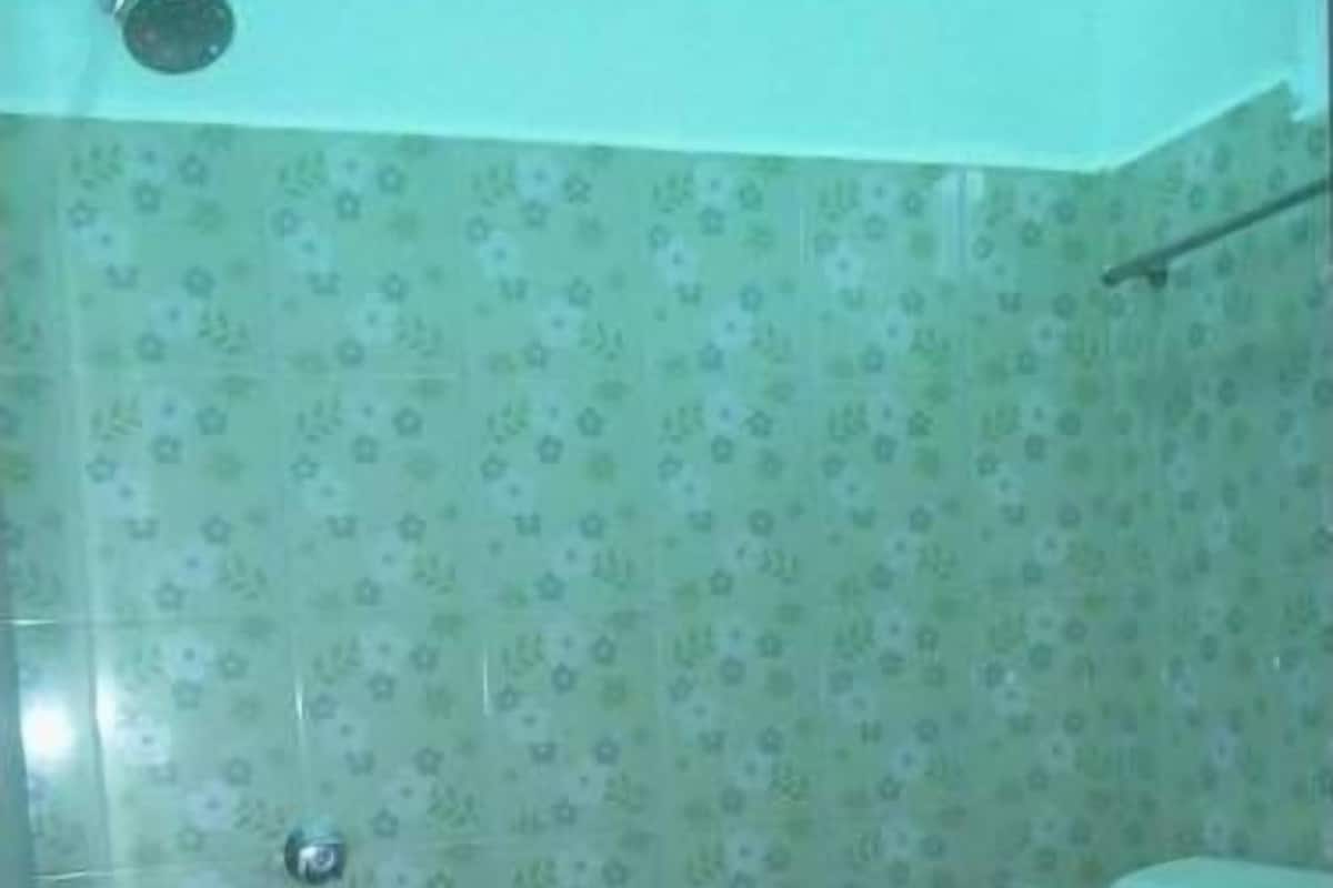 Une salle de bain avec des toilettes, une douche et un mur recouvert de carreaux à motifs floraux.