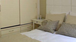 A bedroom with a bed, two bedside tables, a nightstand, and a wardrobe. - Villa St Aubyn (São Vicente)