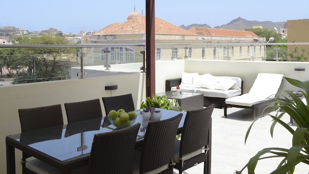 A rooftop terrace with a dining table, chairs, a sofa, and a potted plant. - Villa St Aubyn (São Vicente)