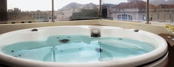 A hot tub with a view of buildings through a window.