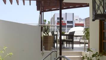 Un balcón con pérgola, mobiliario exterior y vistas a la ciudad.