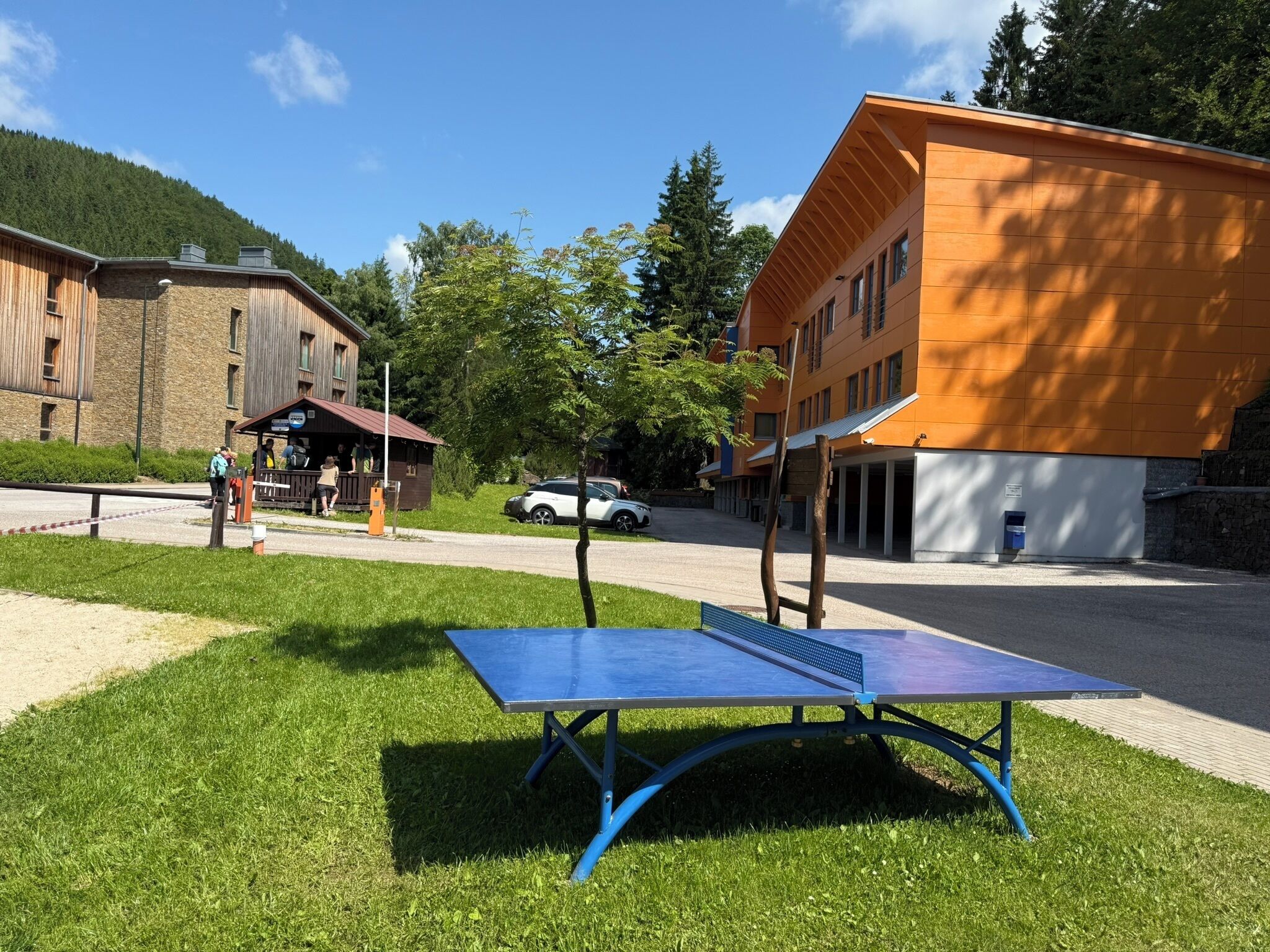 Ein Tischtennistisch in einer grünen Umgebung, im Hintergrund sind Gebäude zu sehen.