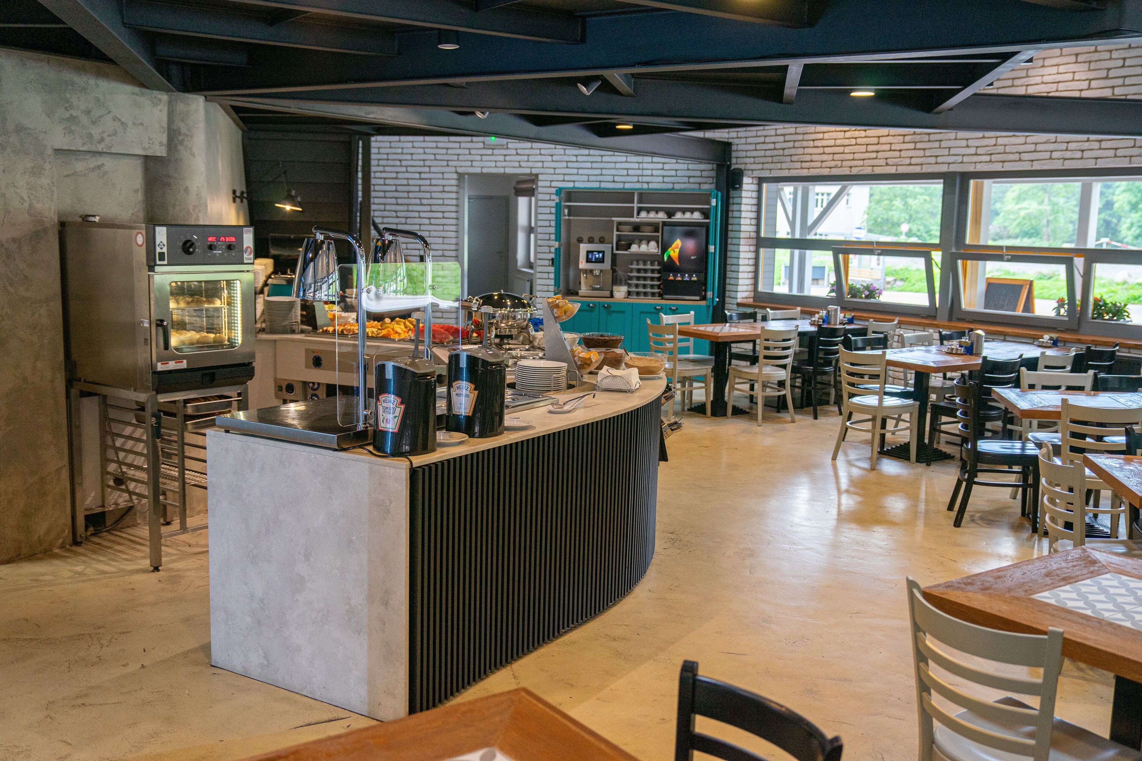 A modern cafe with a central counter, seating area, and a brick wall.