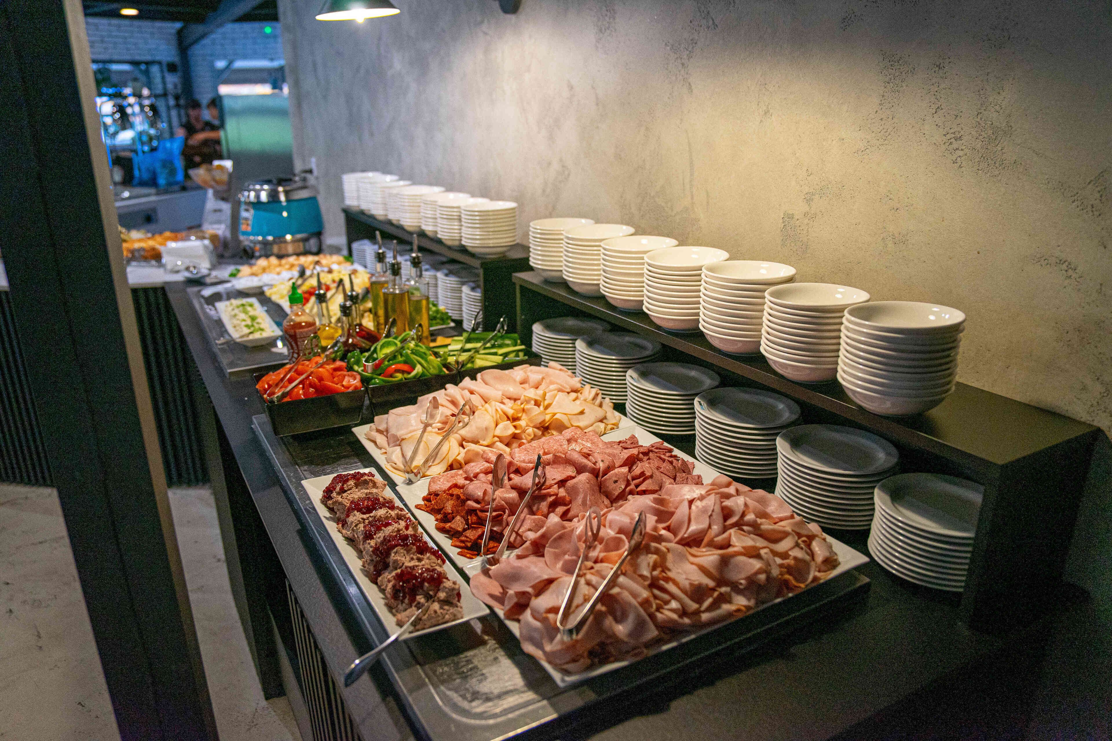 Un buffet proposant une variété de plats et des assiettes blanches empilées.