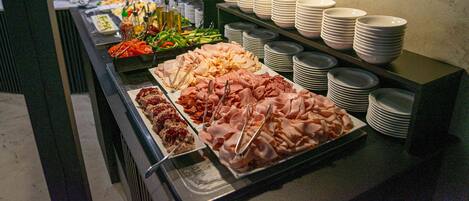Un buffet proposant une variété de plats et des assiettes blanches empilées.
