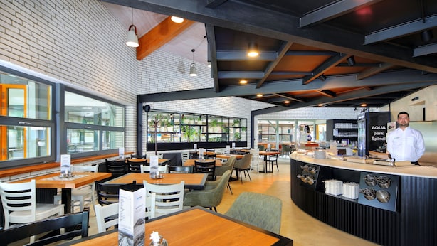 A modern restaurant with a brick wall, wooden tables, and a bar area. - Resort Špindl (Spindleruv Mlyn)
