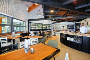 A modern restaurant with a brick wall, wooden tables, and a bar area. - Resort Špindl (Spindleruv Mlyn)