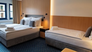 A hotel room with two beds, a wooden headboard, a nightstand, and a window with curtains. - Resort Špindl (Spindleruv Mlyn)