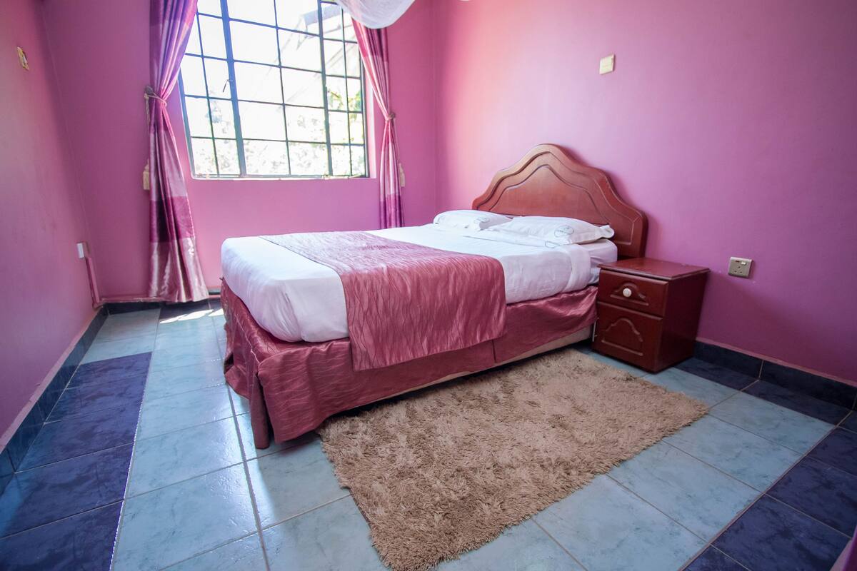 A bedroom with a bed, nightstand, and a window with curtains.