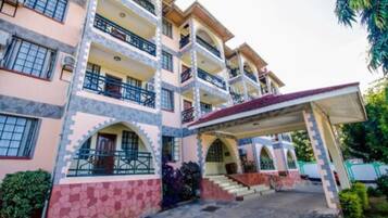 A multi-story hotel with balconies, a covered entrance, and a stone facade.