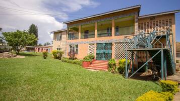 Two-story building with a flat roof and balcony, featuring a combination of brick and plaster exteriors and a lattice design.