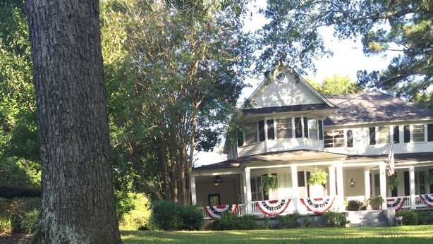 A house with a porch decorated with red, white, and blue banners, and a sign in front reading "1108 Broadway Street". - Huffman House (Minden)