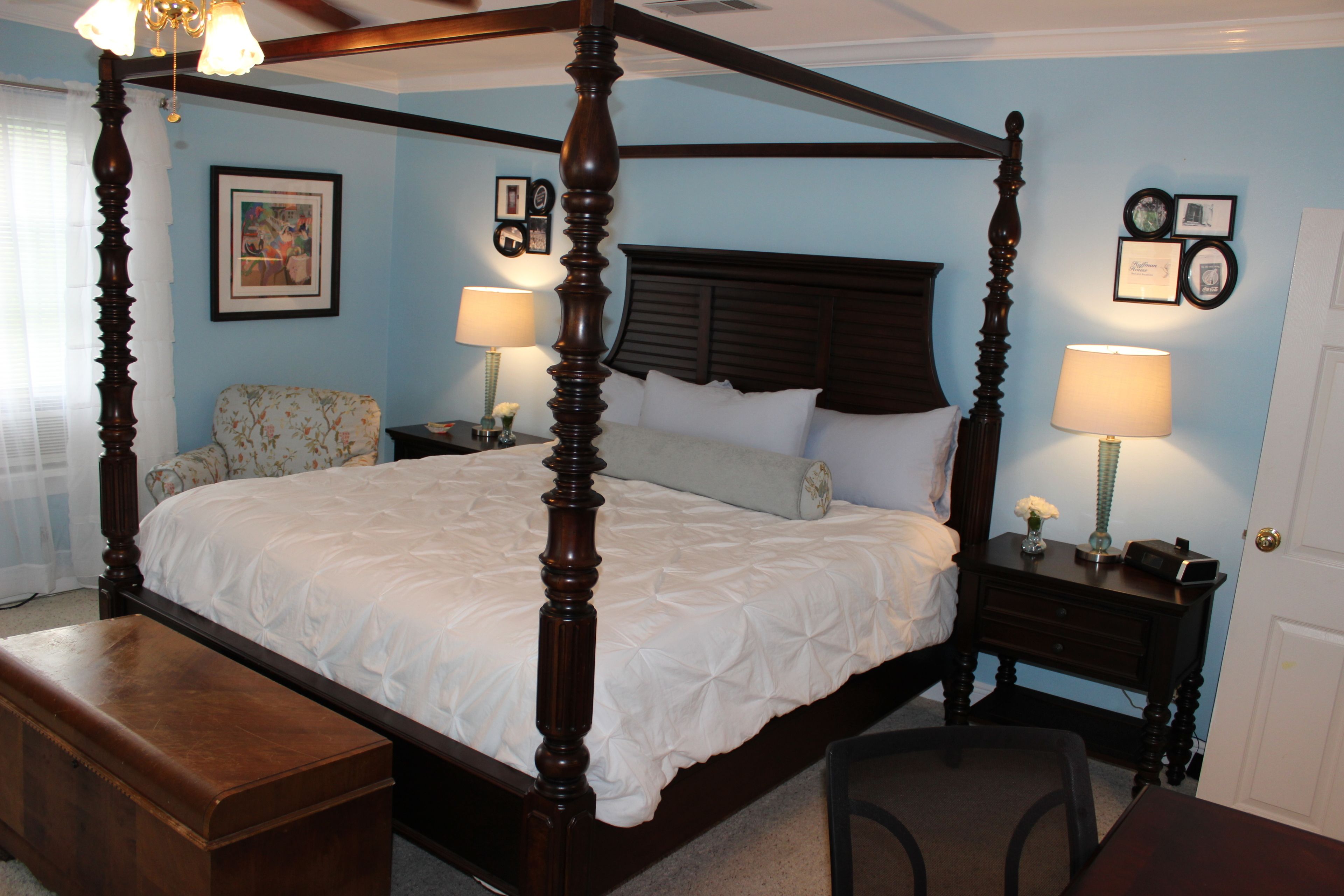 A four-poster bed with a dark wooden frame, a white bedspread, and two bedside tables with lamps.
