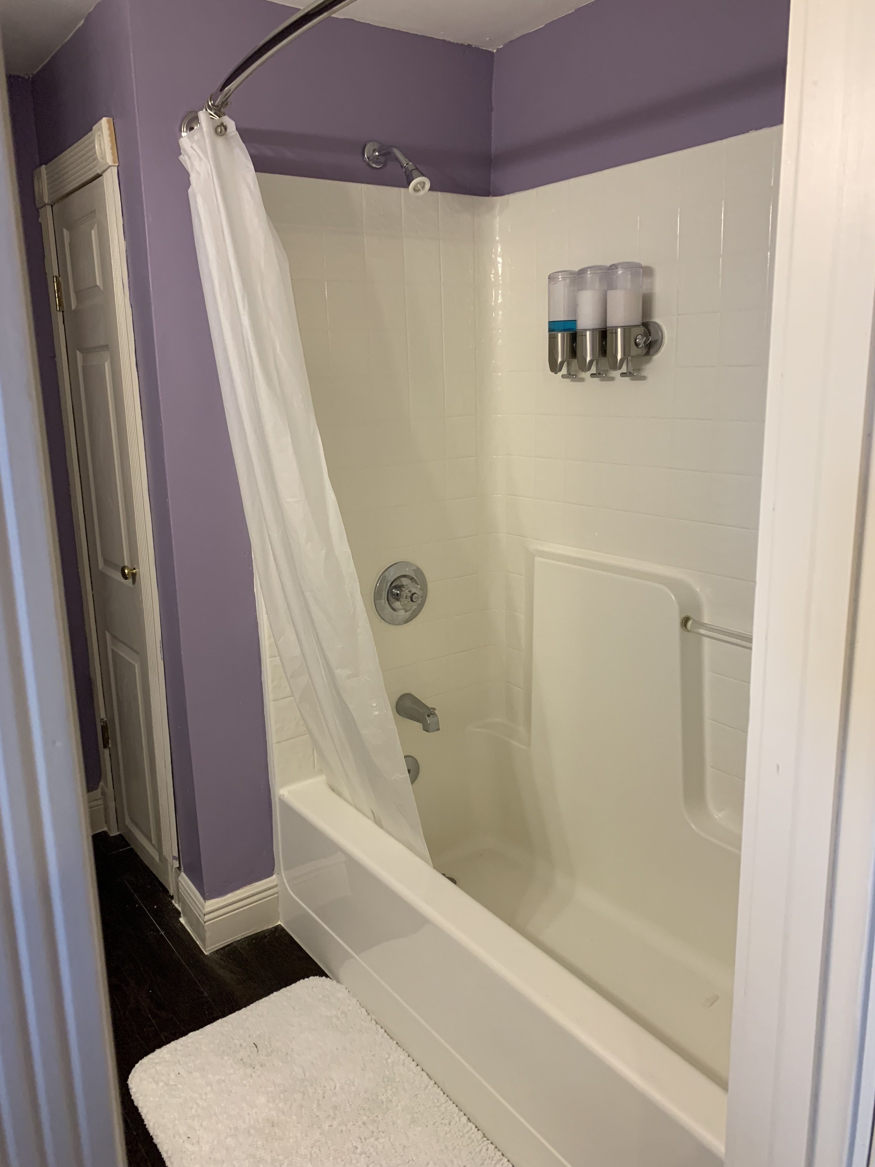 Une douche à l’italienne avec une porte en verre, une baignoire blanche et un rideau de douche.