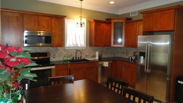 A kitchen with wooden cabinets, stainless steel appliances, and a dining table. - Choo Choo Lofts, 3 br, 2 bath, Full Kitchen - Lafayette, LA (Lafayette)