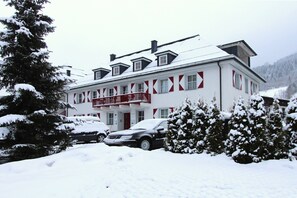 A two-story building with a red balcony and a car parked in front. - Kitz Residenz by Alpin Rentals - incl Summercard (Kaprun)