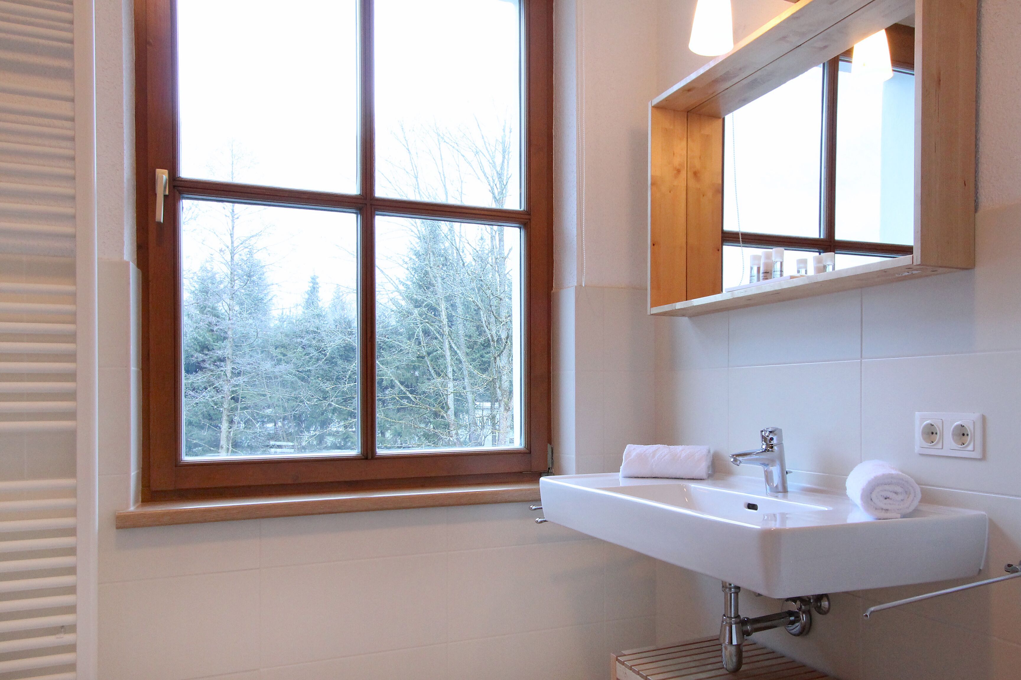 A bathroom with a window, a sink, and a mirror.