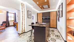 A modern kitchen with a central island, wooden cabinets, and a patterned floor. - Kitz Residenz by Alpin Rentals - incl Summercard (Kaprun)