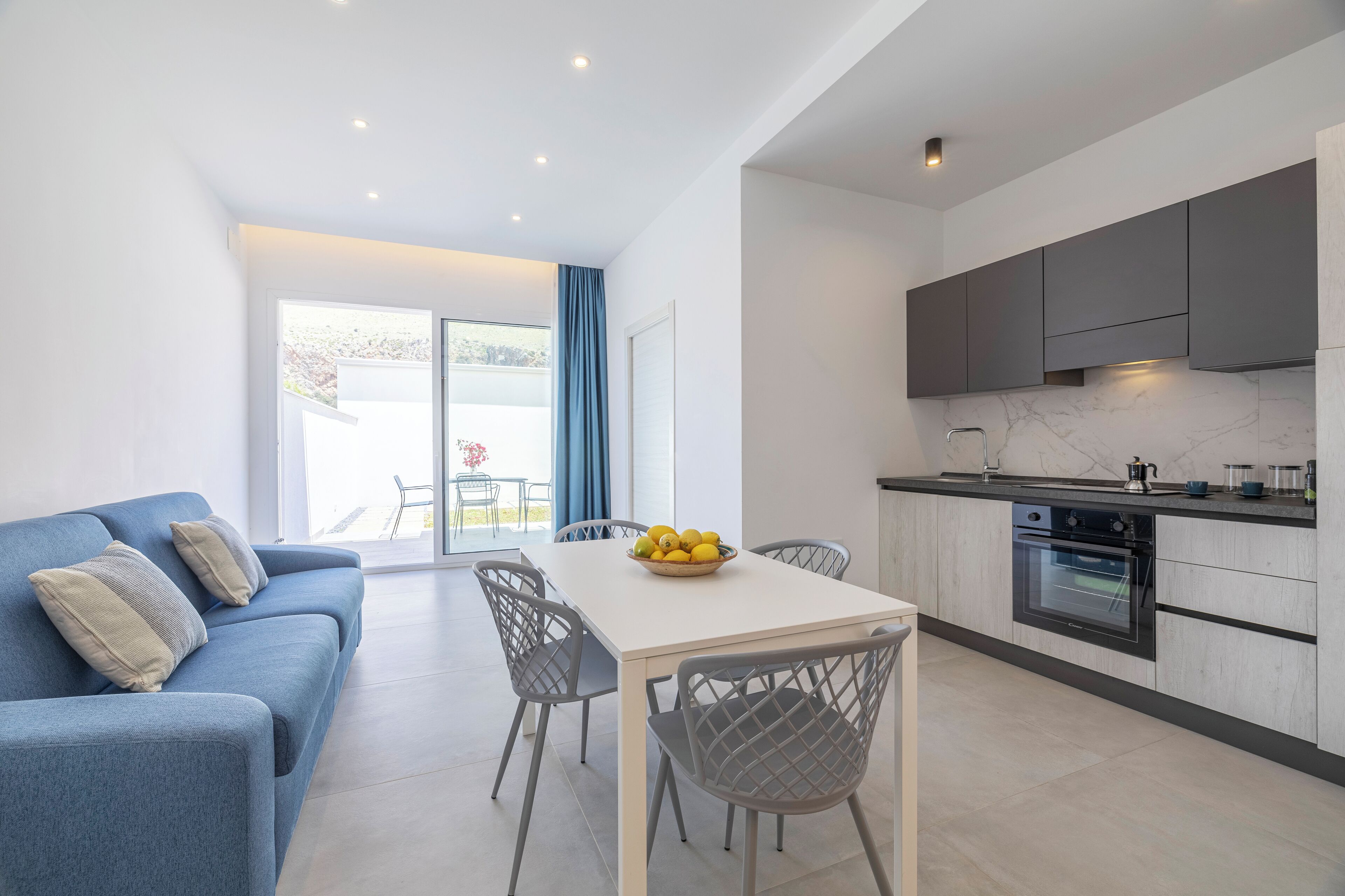 A modern kitchen with a marble countertop, built-in oven, and grey cabinets.