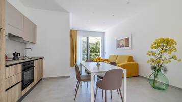 Una cocina moderna con comedor, un sofá amarillo y un amplio ventanal con vistas a zonas verdes.