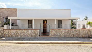 A modern two-story house with a stone facade, a gated entrance, and a small porch.