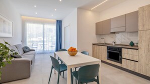 A modern apartment with a dining area, kitchen, and living room. - Case Vacanza Loria (San Vito Lo Capo)