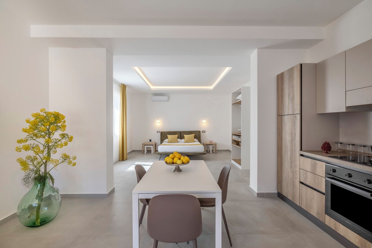 Una habitación de hotel moderna con comedor, kitchenette y dormitorio.