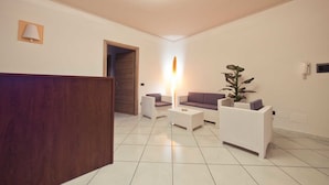 Uma sala de estar moderna com móveis brancos, uma planta grande e um abajur alto e luminoso.