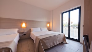 Quarto de hotel com duas camas, varanda e vista, além de uma televisão.