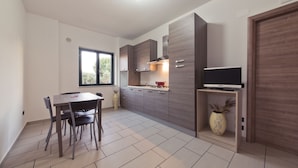Uma cozinha moderna com uma mesa de jantar e cadeiras, uma TV integrada e uma janela que proporciona luz natural.