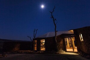 Un edificio de piedra con techo de metal, puerta visible y ambiente interior iluminado.