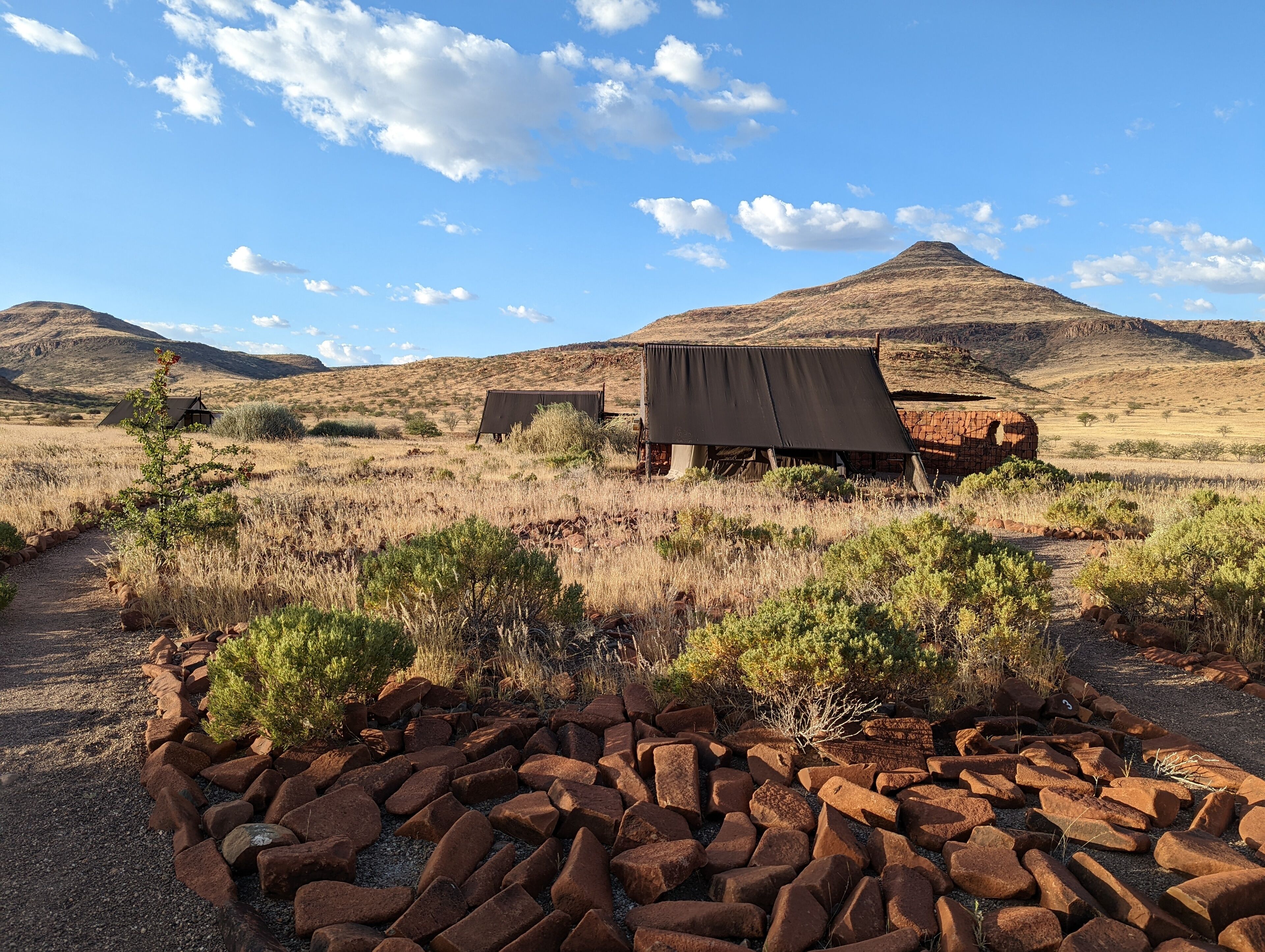 A rustic outdoor setting with a gravel path, a pile of rocks, and a small structure with a roof.