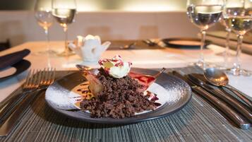 Ein Desserteller mit Schokoladenstreuseln, einer Kugel Eis und einer Zierblume auf einer strukturierten Tischdecke.