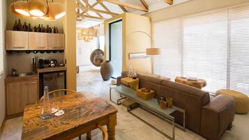 A modern kitchen with wooden cabinets, a dining table, and a cozy living area with a sofa and ottoman.